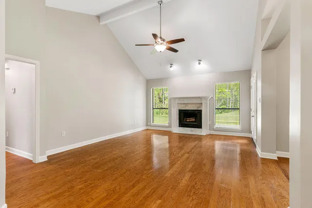a view of empty room with wooden floor fan and window