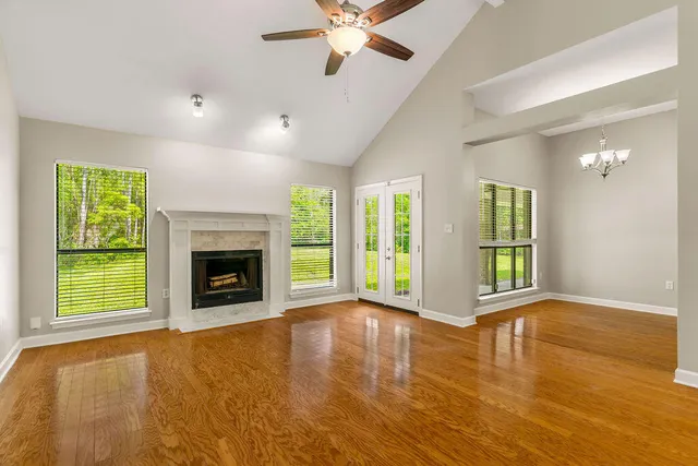 a view of an empty room with window a fireplace and a ceiling fan