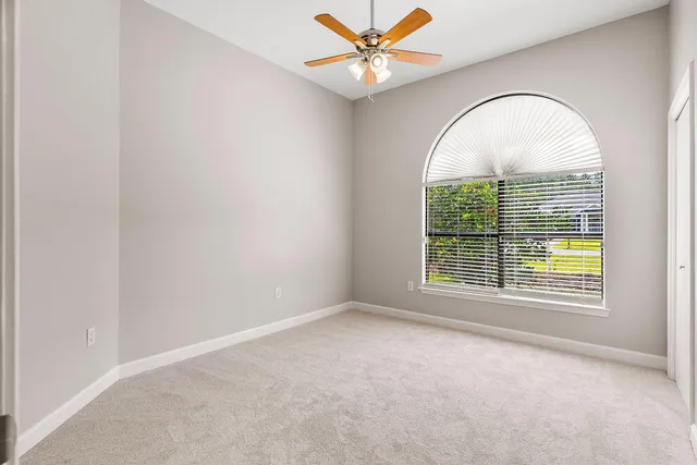 an empty room with a window and a ceiling fan