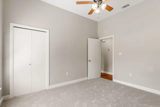 an empty room with a ceiling fan and carpet