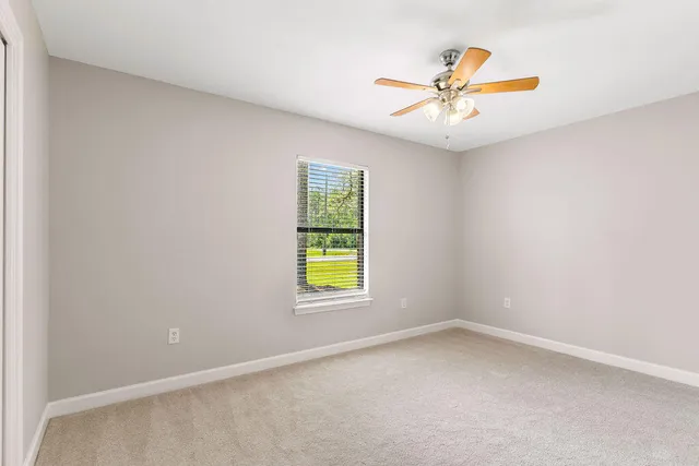 an empty room with window and ceiling fan