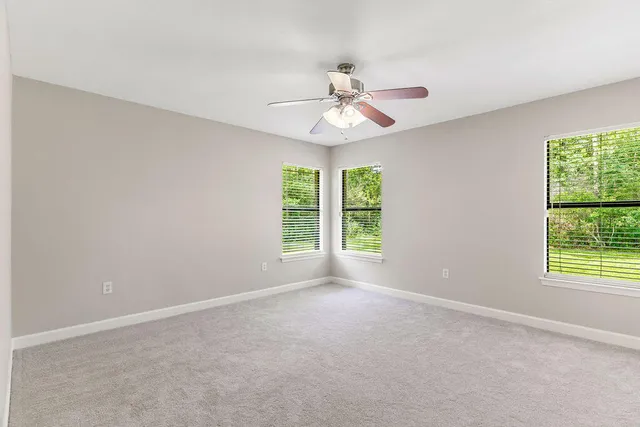 an empty room with windows and fan