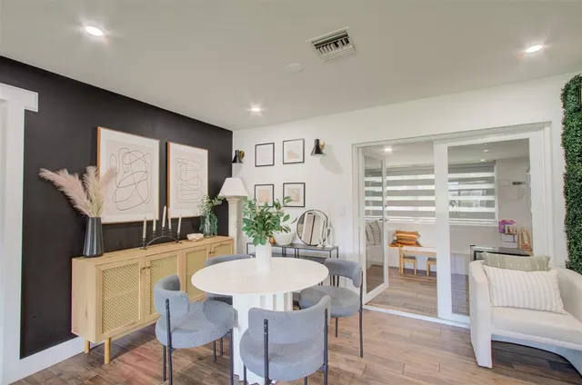 a living room with stainless steel appliances kitchen island granite countertop a dining table chairs workspace and a window