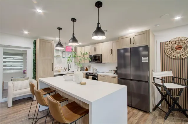 a kitchen with stainless steel appliances granite countertop a dining table chairs refrigerator and microwave