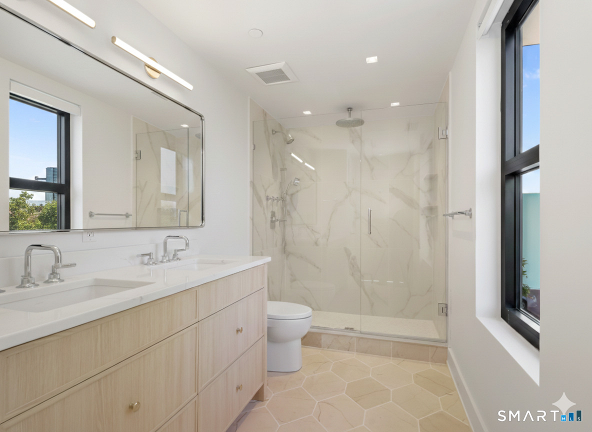 116 Sherman Street, Unit 2 Fairfield, CT 06824 - Photo 29 of 31 a bathroom with a double vanity sink toilet mirror and shower