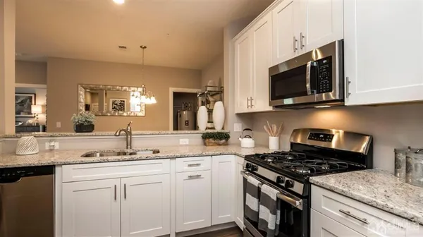 a kitchen with stainless steel appliances granite countertop a sink a stove a microwave oven and cabinets