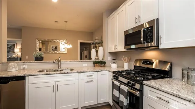 a kitchen with stainless steel appliances granite countertop a sink a stove a microwave oven and cabinets
