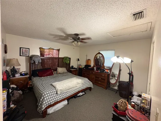 a bedroom with bed a flat tv screen on dresser and a mirror