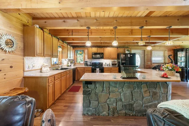 a kitchen with stainless steel appliances kitchen island granite countertop a table chairs in it and a wooden floor