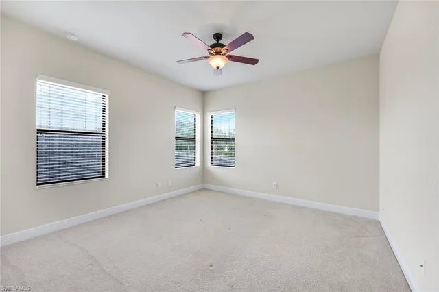 an empty room with window and ceiling fan