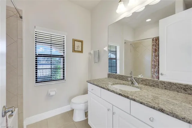 a bathroom with a granite countertop sink toilet and mirror