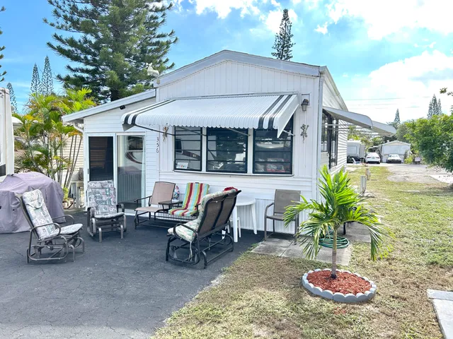 a view of a patio with table and chairs potted plants and large tree