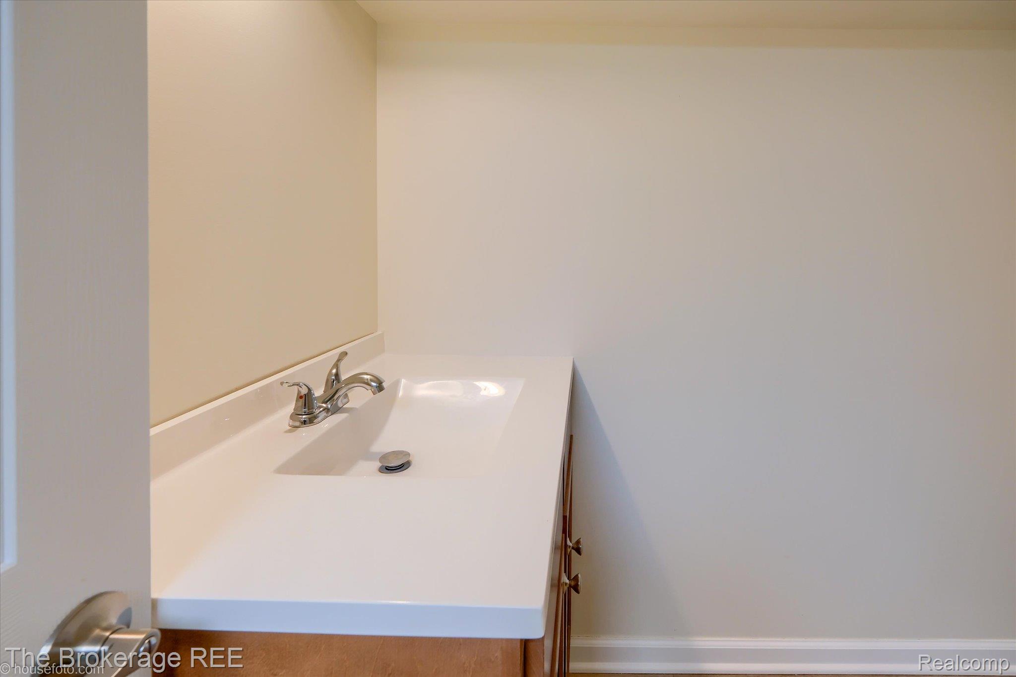 1077 Hadley Road Lapeer, MI 48446 - Photo 44 of 61 Vanity with an integrated white sink, chrome faucet, and wood-finish cabinetry