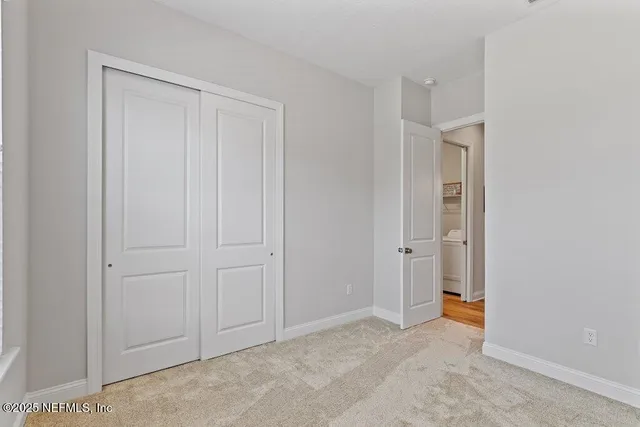 a view of an empty room with window and bathroom