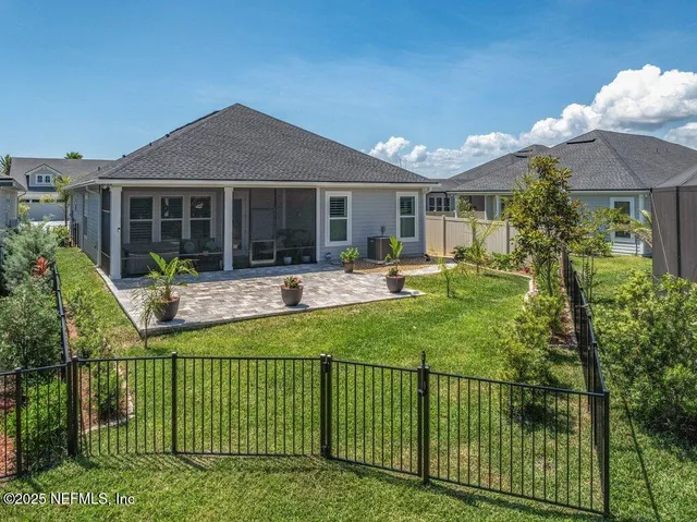 a view of a white house with a large pool and a lawn chair under palm trees