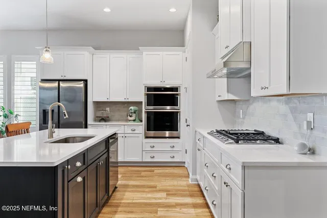 a kitchen with stainless steel appliances granite countertop a sink a stove a refrigerator cabinets and chairs