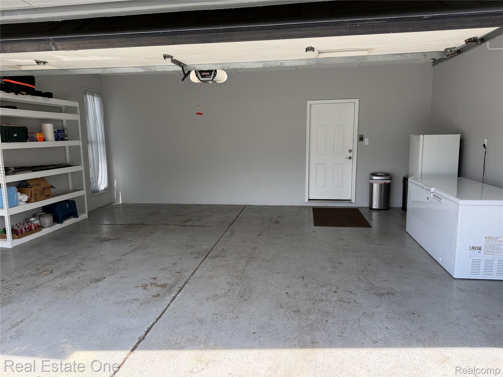 1115 Torpey Road Troy, MI 48083 - Photo 5 of 38 Spacious garage featuring a concrete floor, light gray painted walls, and a white paneled door