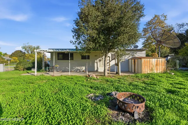 a backyard of a house with table and chairs plants and large tree