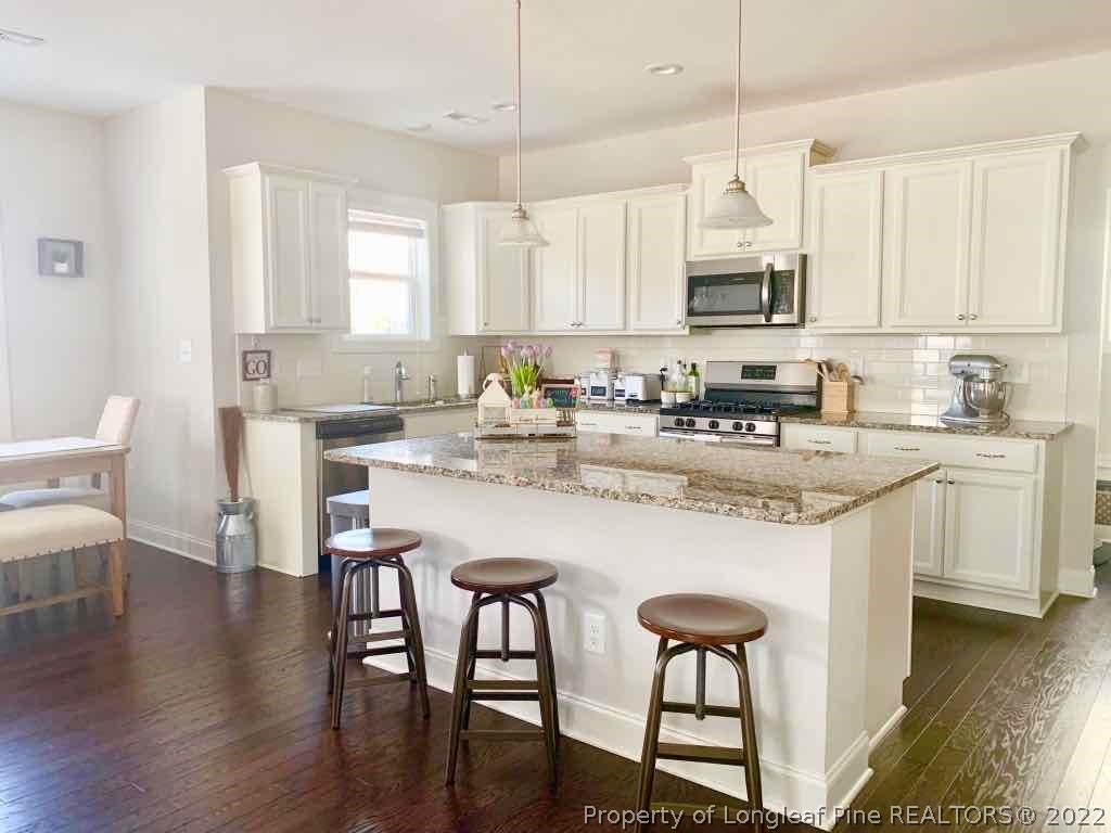 60 Wildlife Bridge Court Spring Lake, NC 28390 - Photo 2 of 5 a kitchen with stainless steel appliances granite countertop a table chairs stove microwave and cabinets