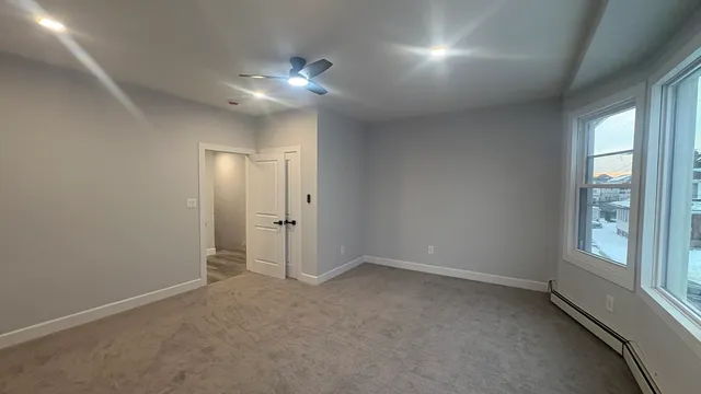 an empty room with chandelier fan and windows