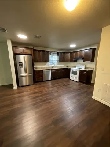 a kitchen with stainless steel appliances wooden floor and a refrigerator