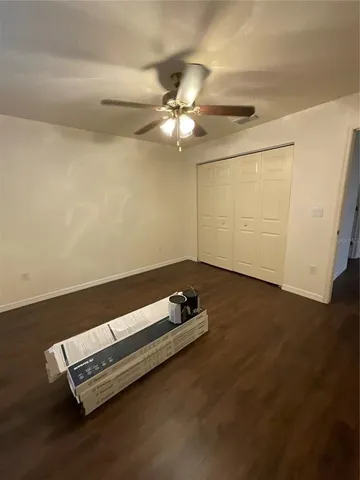 an empty room with wooden floor and fan