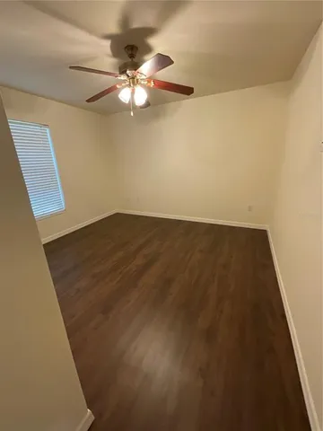 an empty room with wooden floor and fan