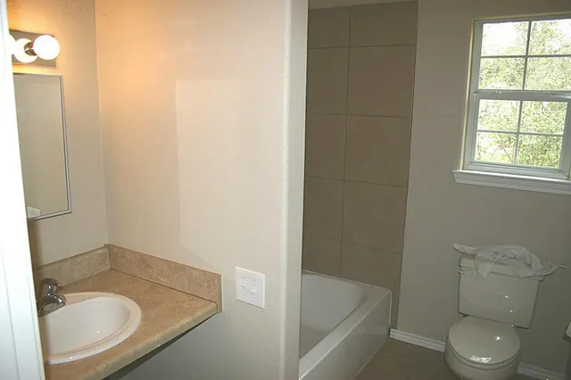 a bathroom with a granite countertop sink toilet and bathtub