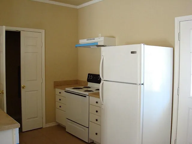 a white refrigerator freezer and a stove sitting inside of a kitchen