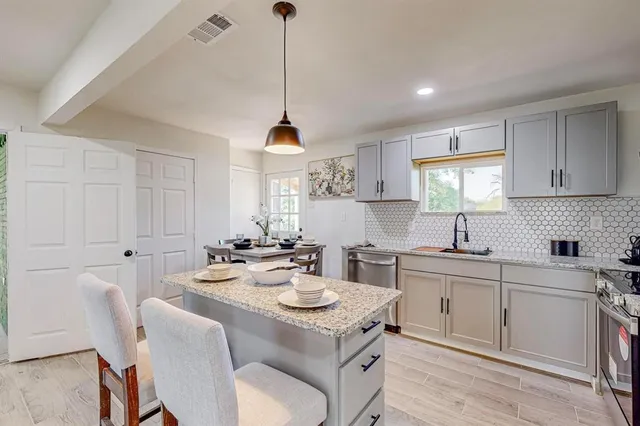 a kitchen with a stove a sink a dining table and chairs