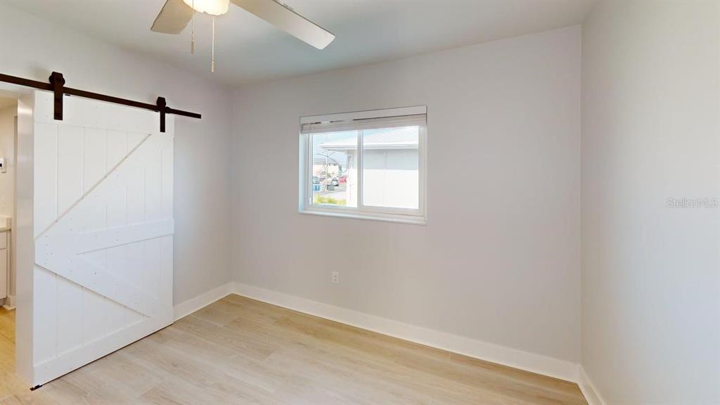 500 129th Avenue East, Unit 1 Madeira Beach, FL 33708 - Photo 11 of 19 a view of a small space with wooden floor a ceiling fan and windows