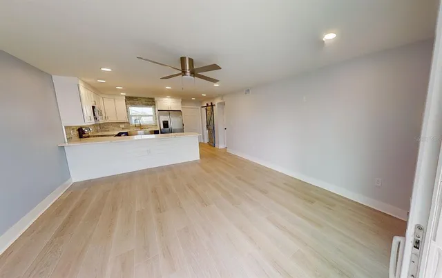 an empty room with wooden floor fan and windows