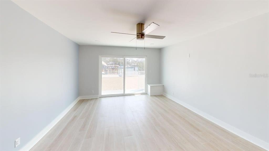 500 129th Avenue East, Unit 1 Madeira Beach, FL 33708 - Photo 7 of 19 an empty room with wooden floor fan and windows