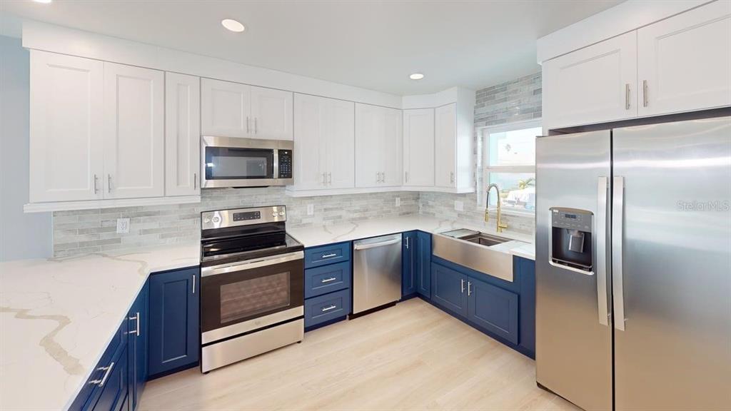 500 129th Avenue East, Unit 1 Madeira Beach, FL 33708 - Photo 8 of 19 a kitchen with granite countertop a refrigerator stove and microwave