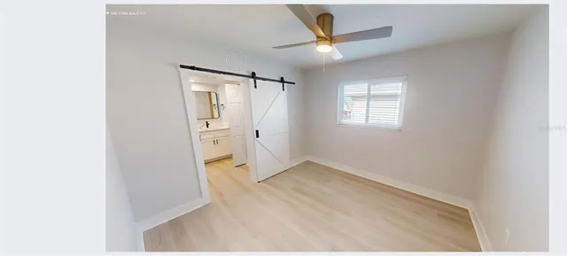 a view of a small space with wooden floor a ceiling fan and windows