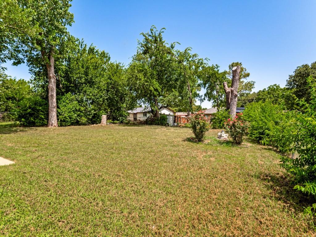 1405 Rambler Road Arlington, TX 76014 - Photo 23 of 26 Expansive grassy area with mature trees and established shrubbery, offering a secluded outdoor environment