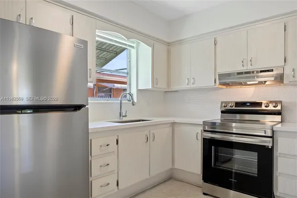 a kitchen with white cabinets and appliances