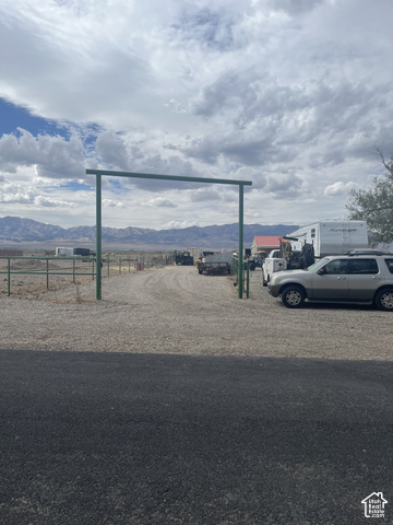 3839 Marshall Road Erda, UT 84029 - Photo 5 of 42 Gravel driveway with a metal archway entry, bordered by a wire fence and distant mountain scenery