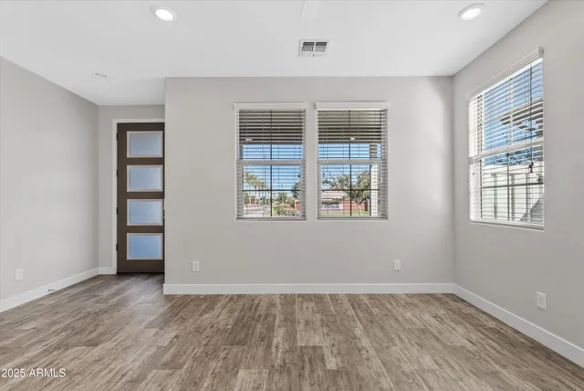 an empty room with wooden floor and windows