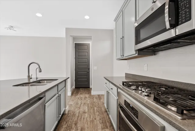 a kitchen with stainless steel appliances a sink dishwasher stove and oven with cabinets