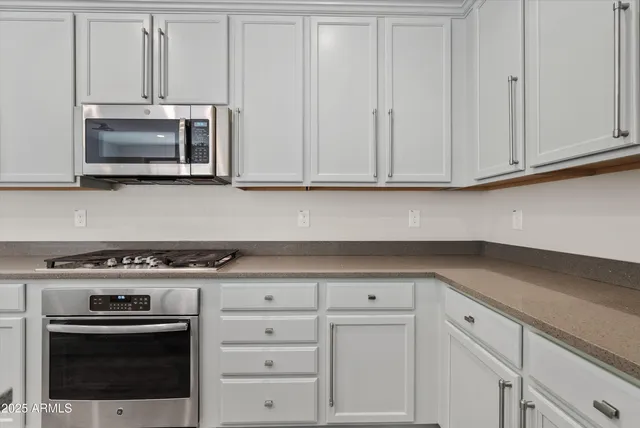 a kitchen with white cabinets and stainless steel appliances
