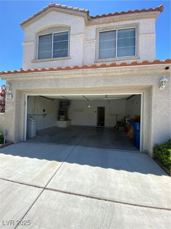 View of front facade with a garage, a tiled roof, and stucco siding