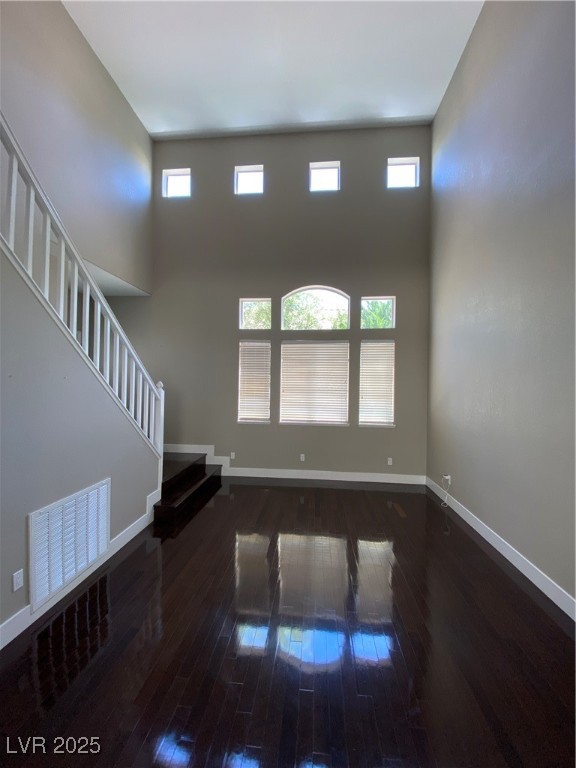 2225 Warm Walnut Drive Las Vegas, NV 89134 - Photo 13 of 38 Unfurnished living room featuring hardwood / wood-style floors, healthy amount of natural light, stairs, and a towering ceiling