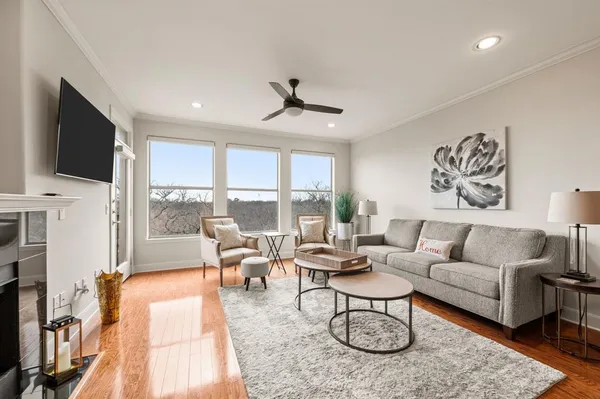 a living room with furniture a flat screen tv and a floor to ceiling window