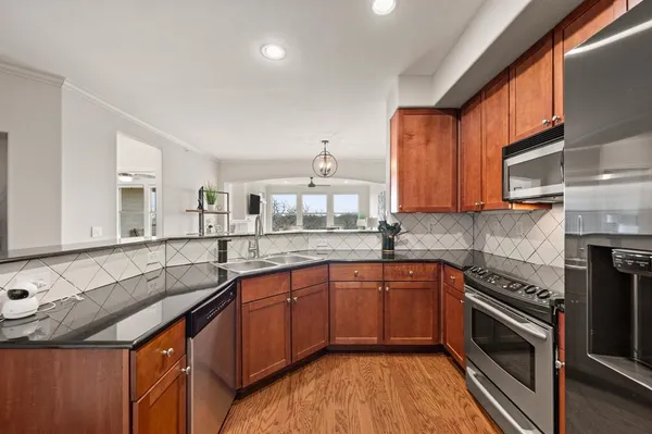 a kitchen with granite countertop a sink stainless steel appliances and cabinets