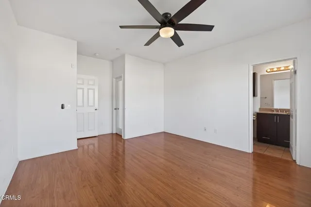 an empty room with wooden floor cabinet and a ceiling fan