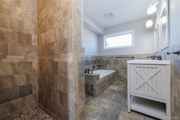a bathroom with a granite countertop sink a mirror and bathtub