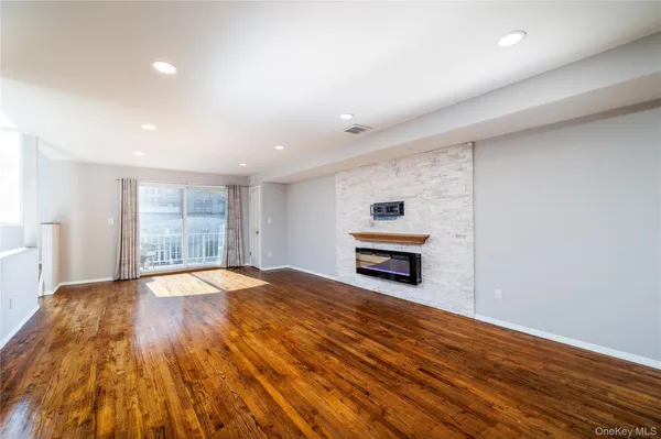 a view of empty room with wooden floor and fireplace