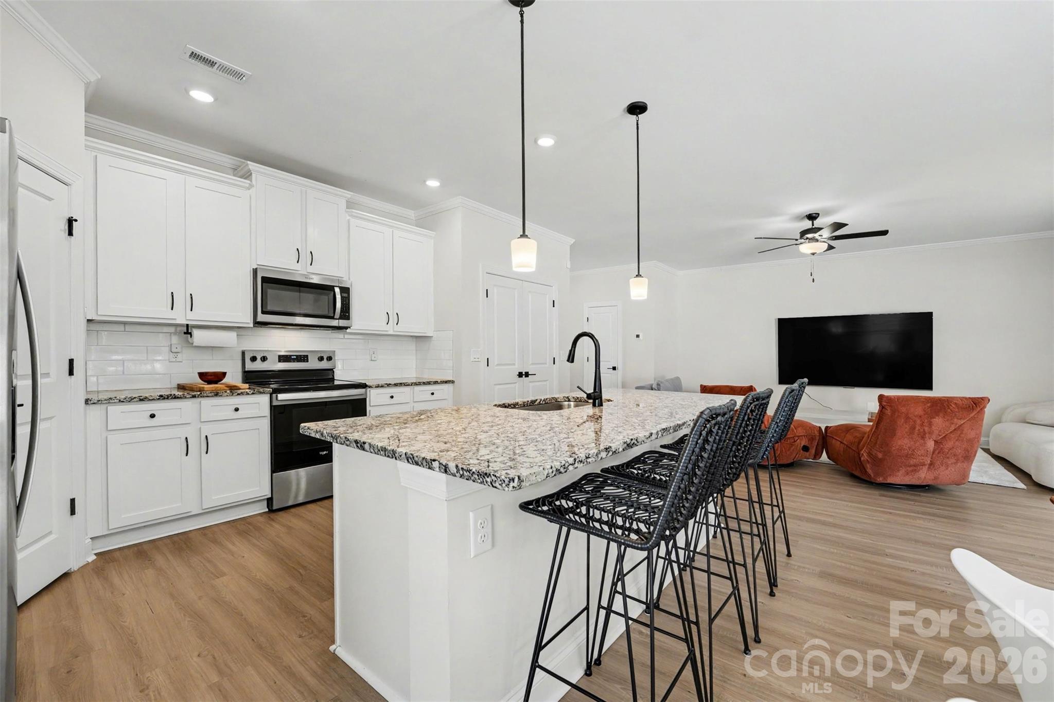 123 Brixham Loop Troutman, NC 28166 - Photo 3 of 18 a kitchen with stainless steel appliances granite countertop a kitchen island a stove a sink a microwave a dining table and chairs