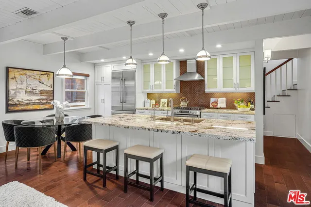 a kitchen with granite countertop a stove a sink a dining table and chairs with wooden floor